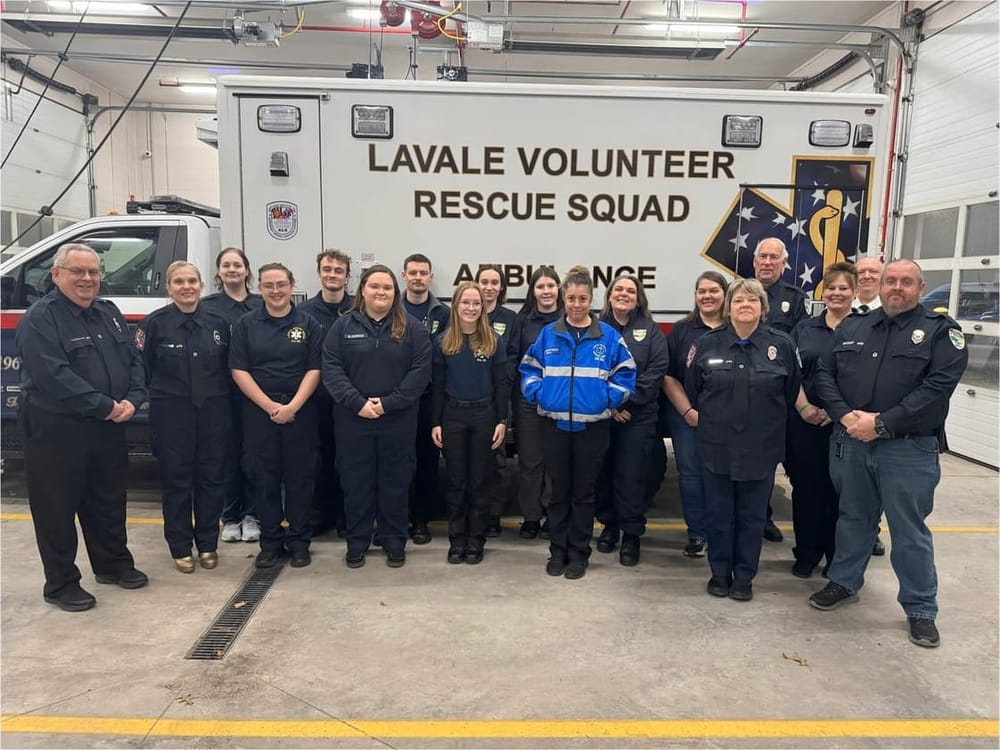 Members of LaVale Volunteer Rescue Squad in uniform, standing together in front of an ambulance in the station bay